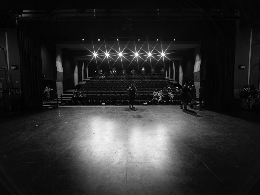 Zwart-witbeeld van een verlicht theaterpodium met publiek in de zaal